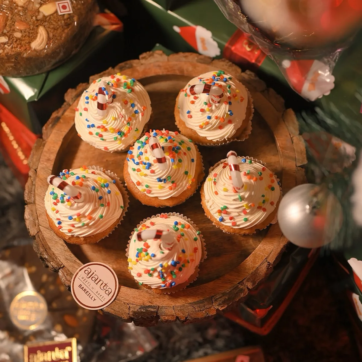 Ajanta Christmas cupcakes with candy cane toppers on branded wooden tray